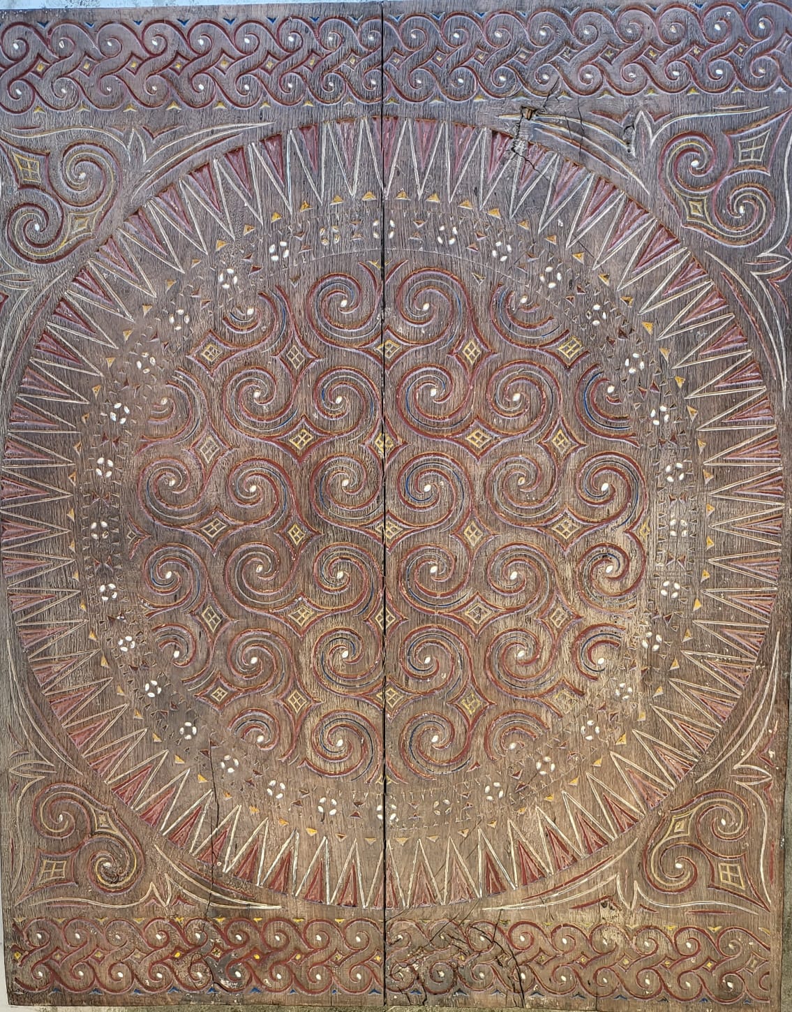Detail of an intricately hand-carved Toraja wooden panel with spiral and geometric motifs